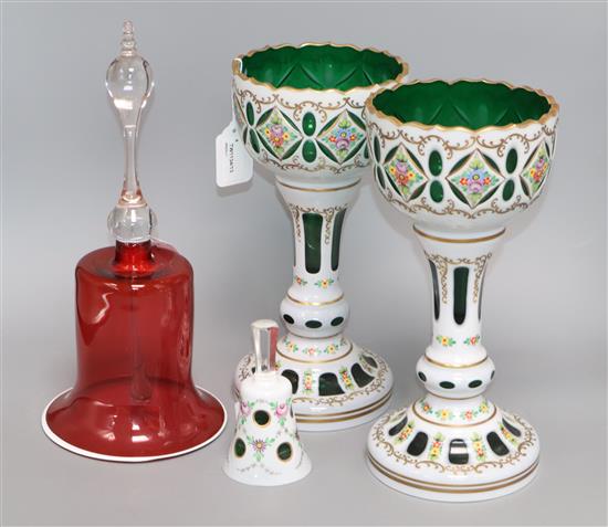 A pair of Bohemian green glass and white overlay chalices with floral decoration, a similar bell and a large ruby glass bell